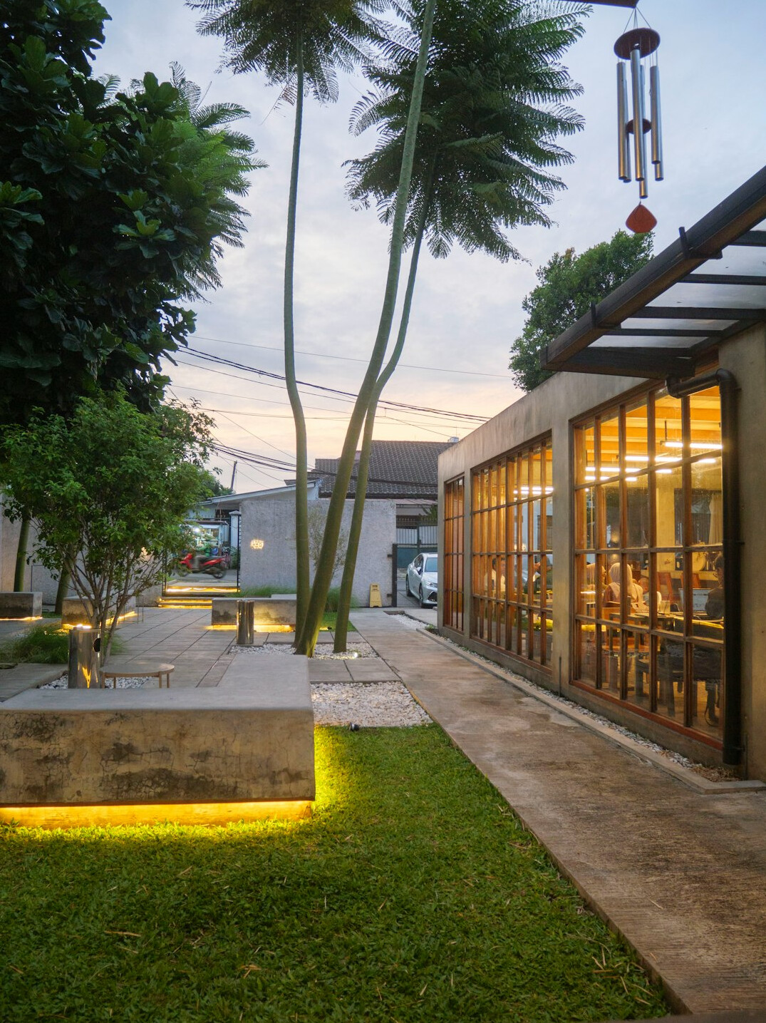Modern villa architecture with glass facade and garden at dusk